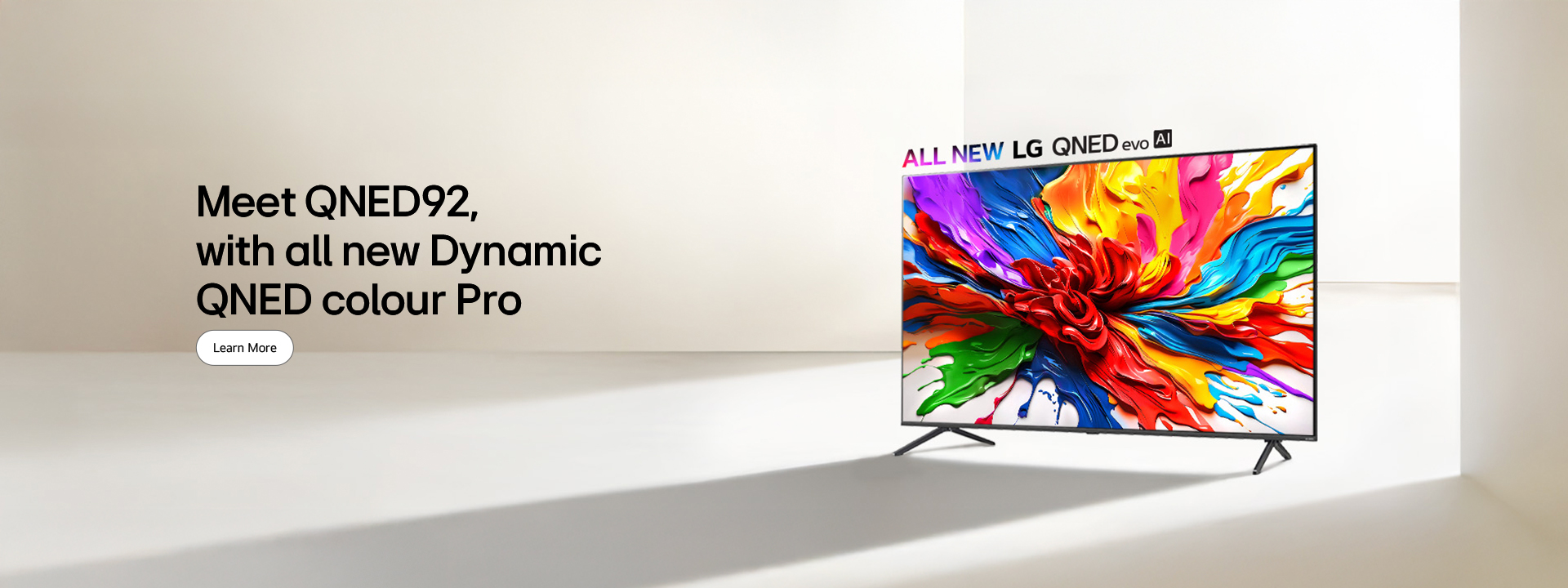 LG QNED TV on a stand in a dominantly white space. On the TV screen is a colorful splash of paint showcasing how QNED TVs can display a wide range of vibrant colors with pleasing contrast. The all new LG QNED evo AI logo is positioned above the TV. 